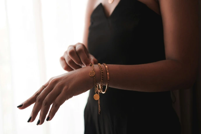 A woman in a black dress holding onto a bracelet